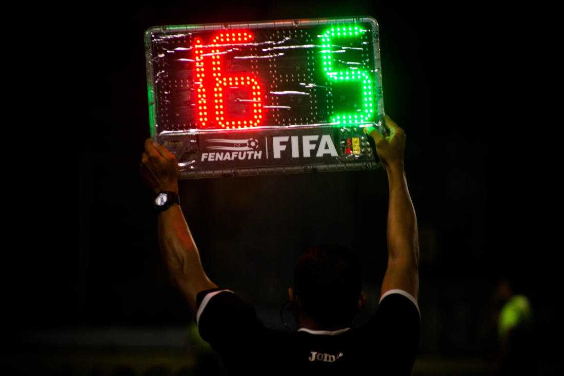 Football official holding a board to indicate substitutions and added
time